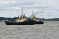 Tugs lead out a container ship from the port from Felixstowe UK